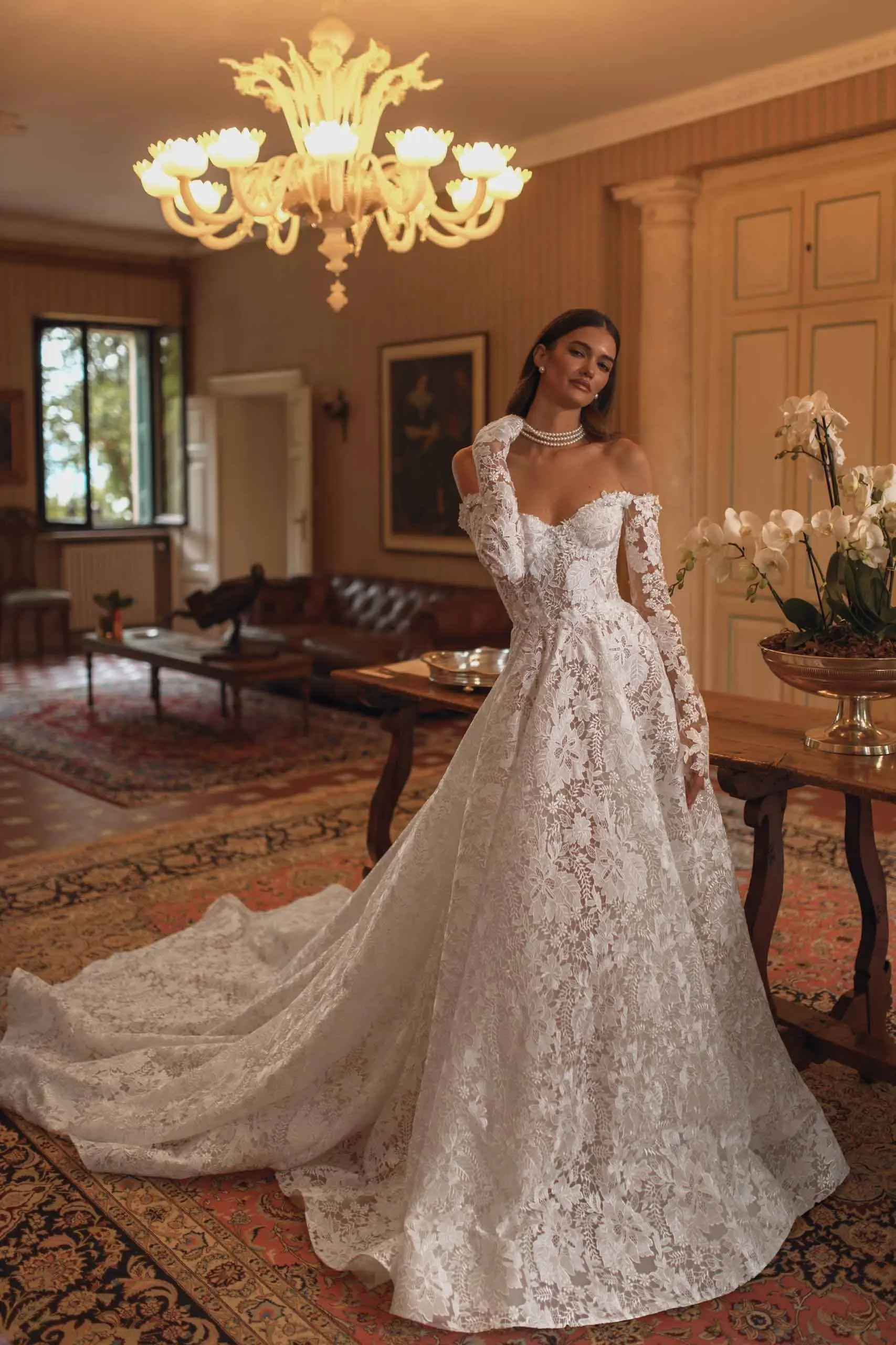 model is wearing a lace off the shoulder long sleeve a-line wedding dress