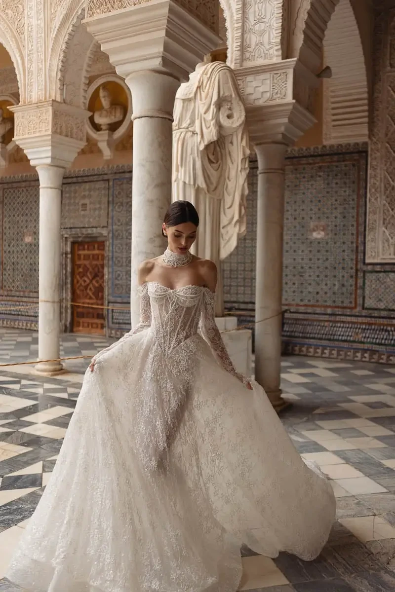 model is wearing an off the shoulder long sleeve lace sheer wedding dress